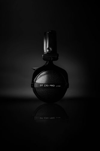 Side view of Beyerdynamic DT 770 PRO headphones placed upright on a reflective black surface.