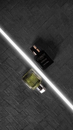 Silver and green Eternity Intense perfume bottle on a rugged clay-toned surface.