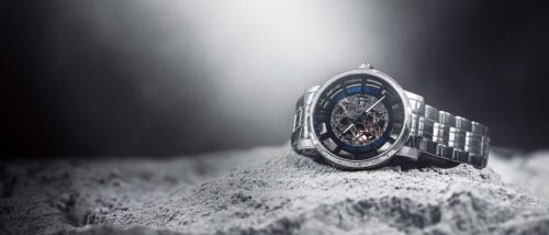 Kenneth Cole Skeleton wristwatch positioned dramatically on rocky terrain with foggy light in the background.