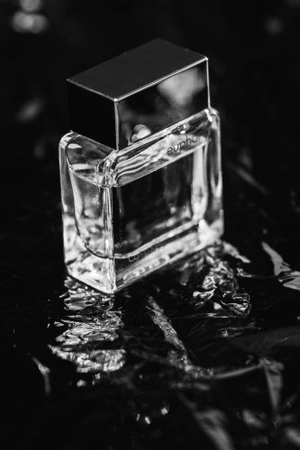 Calvin Klein Euphoria perfume bottle placed on crinkled reflective black surface in monochrome.