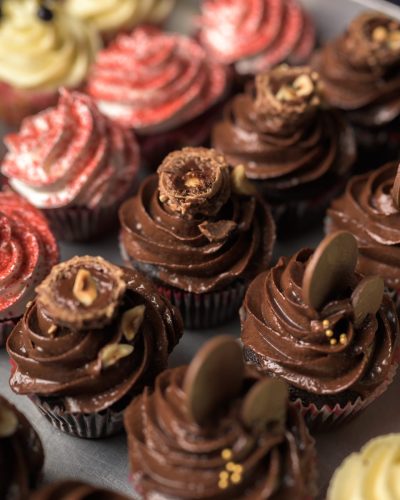 Assorted chocolate and strawberry cupcakes with rich swirled frosting.